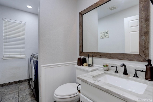 9079 Garnet St, Highlands Ranch, CO 80126 - bathroom with washer and clothes dryer, vanity, toilet, and wainscoting