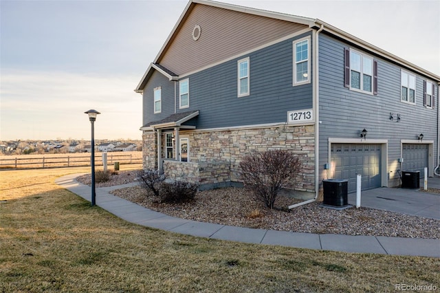 view of property exterior with a lawn, a garage, and central AC