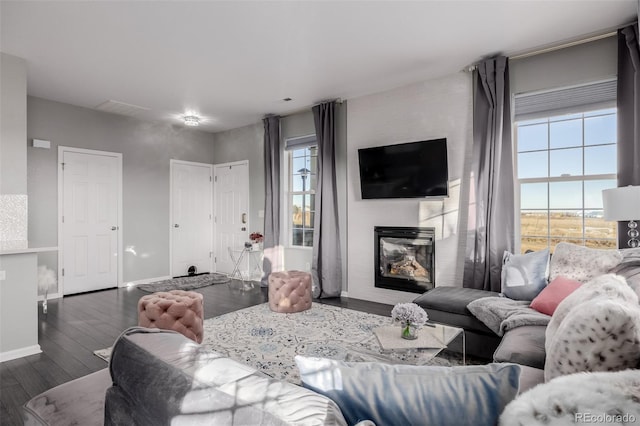 living room with a large fireplace and dark wood-type flooring