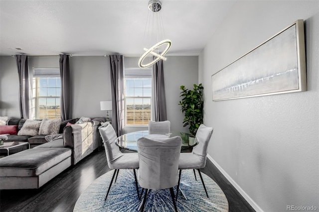 dining room with plenty of natural light, dark wood-type flooring, and a notable chandelier