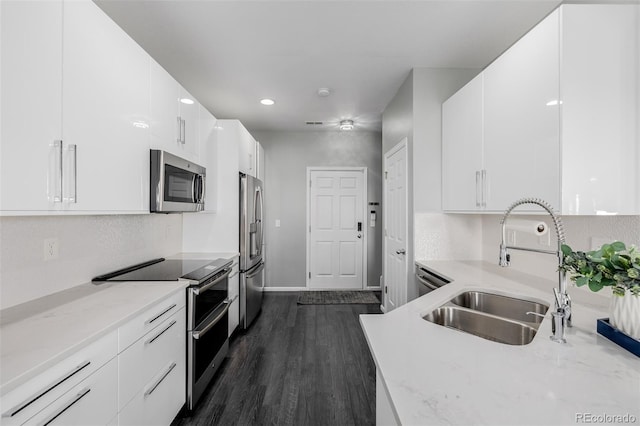 kitchen featuring white cabinetry, sink, light stone counters, dark hardwood / wood-style floors, and appliances with stainless steel finishes