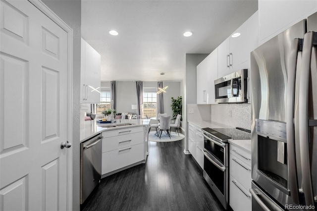 kitchen with white cabinets, stainless steel appliances, hanging light fixtures, and dark wood-type flooring