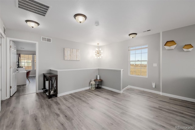 empty room with a chandelier, hardwood / wood-style floors, and a healthy amount of sunlight