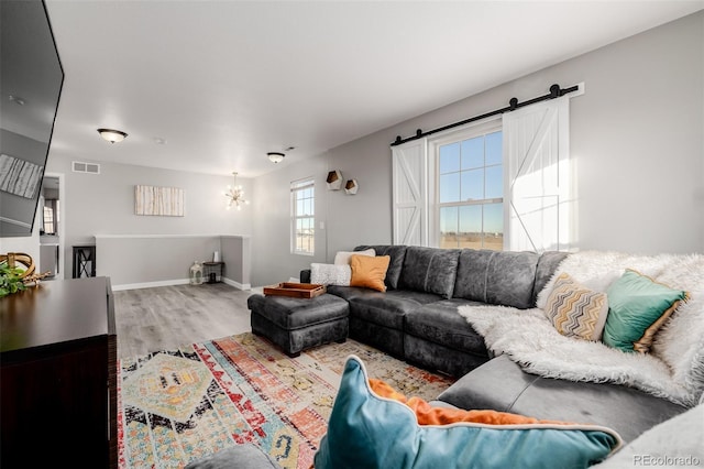 living room featuring a barn door, hardwood / wood-style flooring, and an inviting chandelier