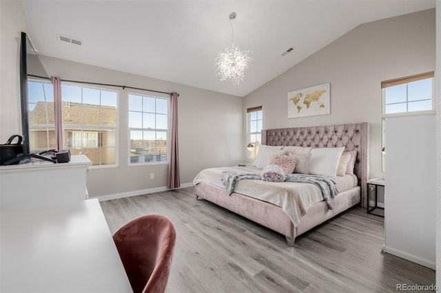 bedroom with light hardwood / wood-style floors, vaulted ceiling, multiple windows, and a notable chandelier