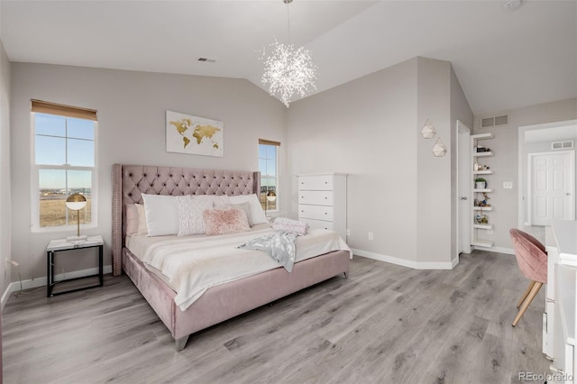 bedroom featuring light hardwood / wood-style flooring, lofted ceiling, and an inviting chandelier