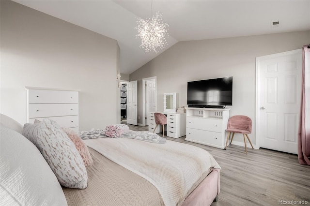 bedroom featuring light hardwood / wood-style floors, lofted ceiling, and a notable chandelier