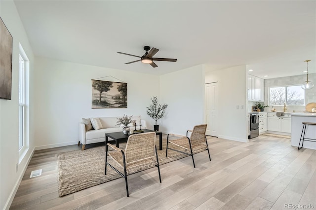 living room with ceiling fan and light hardwood / wood-style floors