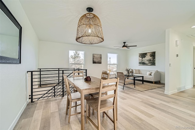 dining room with ceiling fan with notable chandelier and light hardwood / wood-style flooring