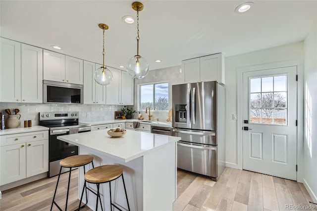 kitchen featuring a center island, light wood finished floors, stainless steel appliances, tasteful backsplash, and light countertops