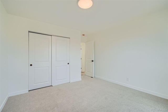 unfurnished bedroom with light colored carpet and a closet