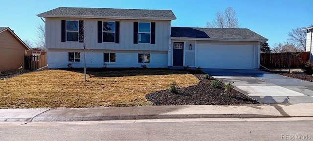 split level home with driveway, a garage, fence, and a front lawn