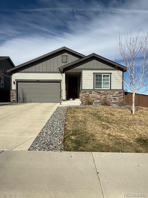 view of front of home with stone siding, board and batten siding, an attached garage, and concrete driveway