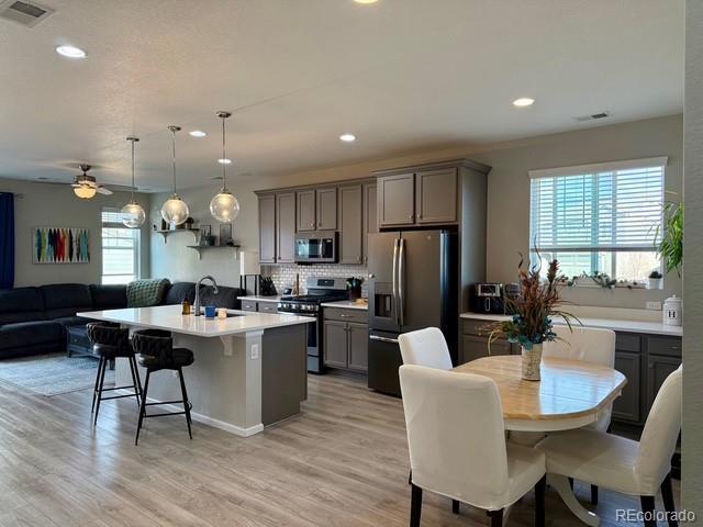 kitchen with visible vents, gray cabinetry, a sink, open floor plan, and stainless steel appliances