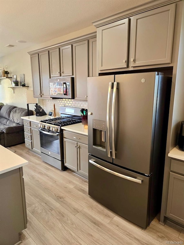 kitchen with gray cabinets, appliances with stainless steel finishes, light countertops, and light wood-type flooring