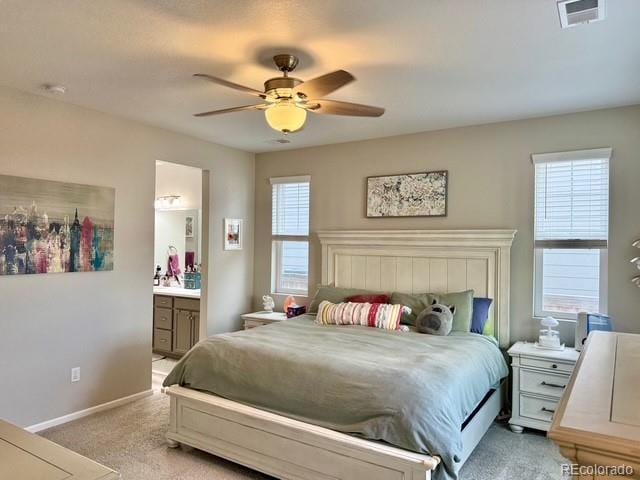 bedroom with visible vents, baseboards, ensuite bath, ceiling fan, and light colored carpet