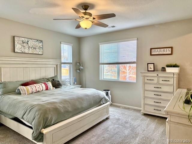 bedroom featuring light carpet, multiple windows, a ceiling fan, and baseboards