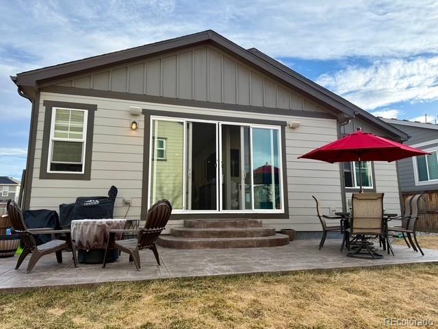 rear view of house with entry steps, a patio, a yard, and board and batten siding