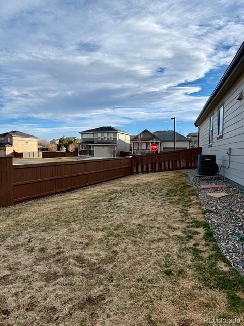 view of yard featuring central AC and fence