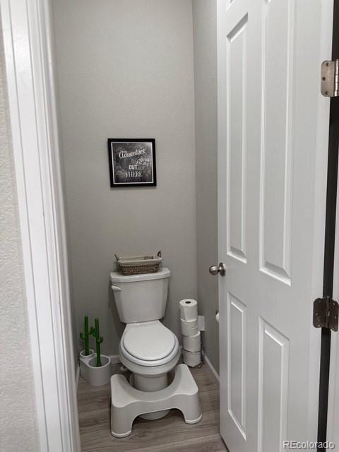 bathroom featuring toilet, baseboards, and wood finished floors