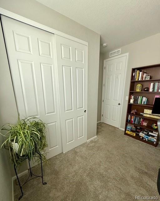 interior space featuring visible vents, baseboards, a textured ceiling, and carpet flooring