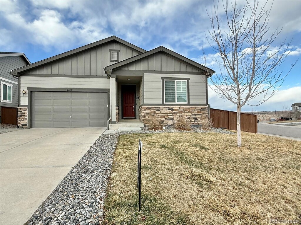 view of front of home featuring board and batten siding, concrete driveway, a garage, and stone siding