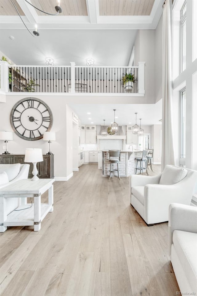 interior space with light hardwood / wood-style flooring, wooden ceiling, a chandelier, and a towering ceiling