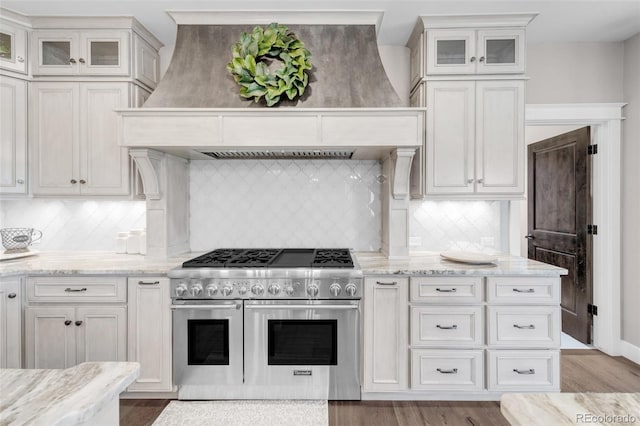 kitchen featuring light hardwood / wood-style floors, range with two ovens, and decorative backsplash