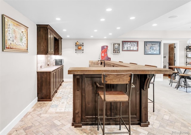 interior space with backsplash, dark brown cabinetry, and light colored carpet