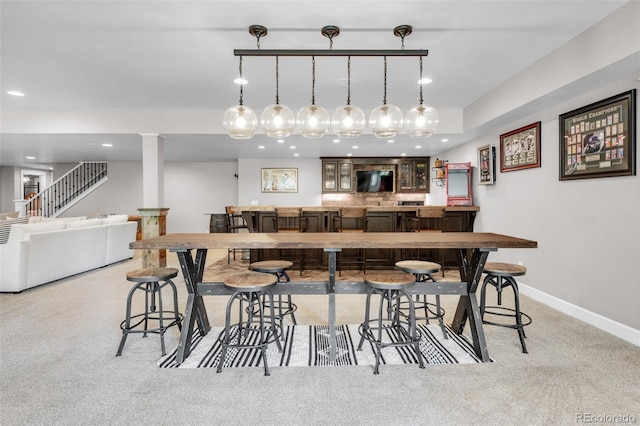 bar featuring light colored carpet and hanging light fixtures