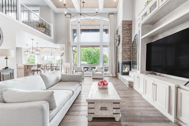 living room featuring wooden ceiling, a stone fireplace, hardwood / wood-style flooring, and a towering ceiling