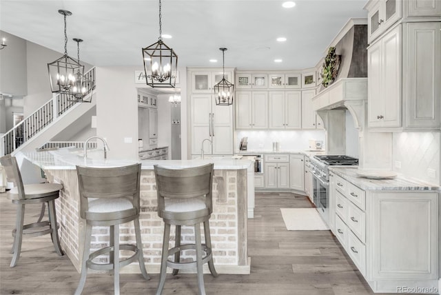 kitchen featuring decorative backsplash, light hardwood / wood-style flooring, range with two ovens, and pendant lighting