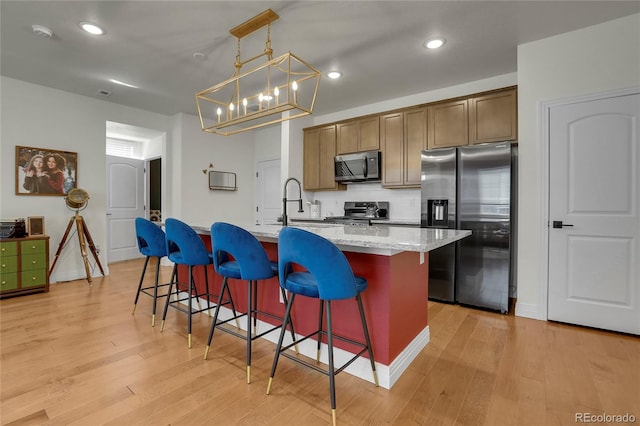 16818 E 119th Ave Unit A, Commerce City, CO 80022 - kitchen featuring stainless steel appliances, light wood-style flooring, a kitchen island with sink, a chandelier, and recessed lighting