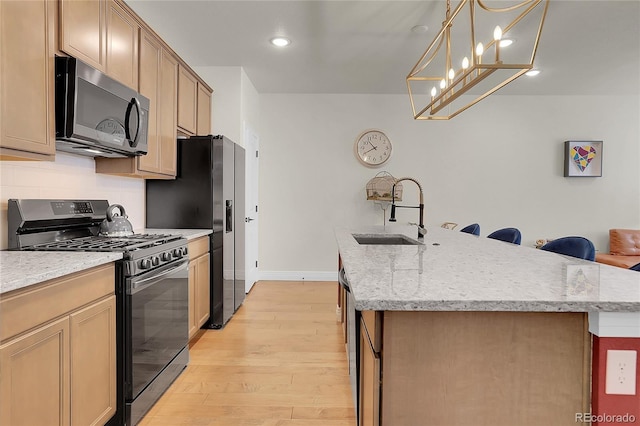 16818 E 119th Ave Unit A, Commerce City, CO 80022 - kitchen featuring stainless steel appliances, a sink, light wood finished floors, a kitchen island with sink, and light stone counters