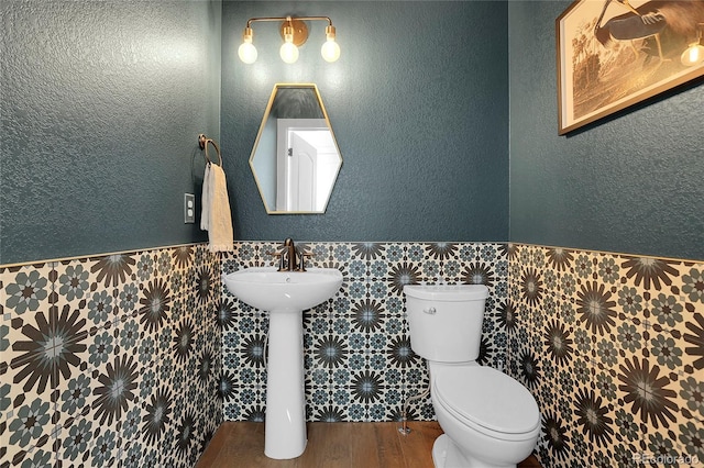 16818 E 119th Ave Unit A, Commerce City, CO 80022 - half bathroom with tile walls, a wainscoted wall, wood finished floors, toilet, and a sink