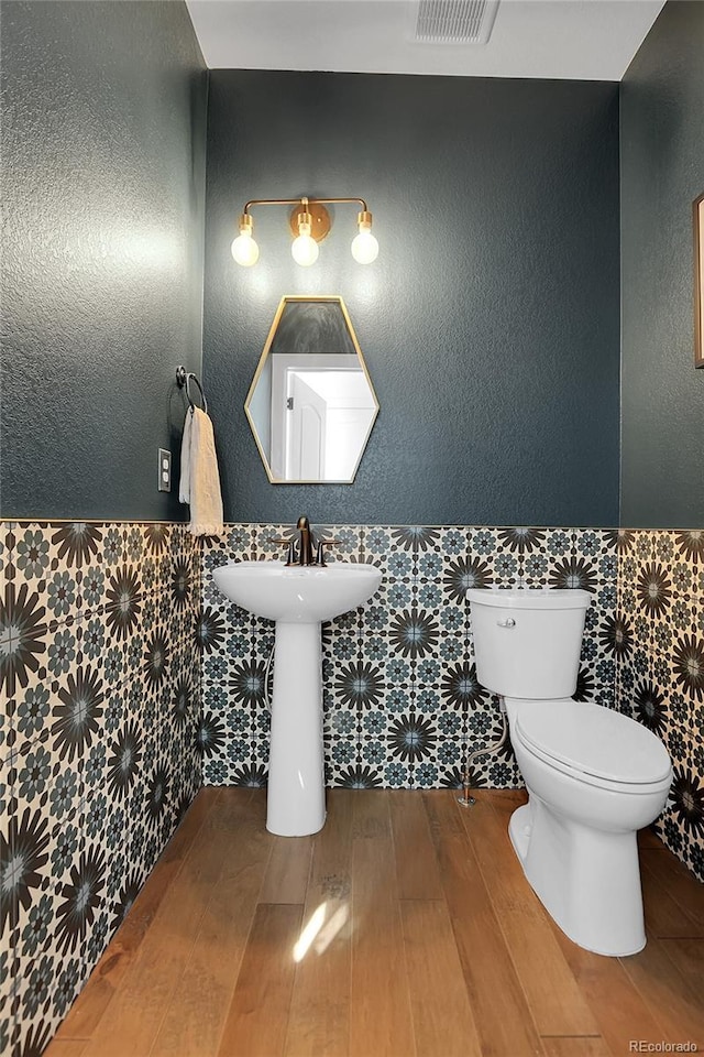 16818 E 119th Ave Unit A, Commerce City, CO 80022 - half bath with wood-type flooring, a wainscoted wall, toilet, tile walls, and a sink