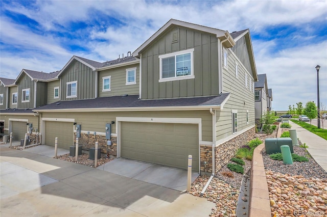 16818 E 119th Ave Unit A, Commerce City, CO 80022 - view of front facade with board and batten siding, an attached garage, stone siding, and driveway