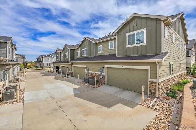 16818 E 119th Ave Unit A, Commerce City, CO 80022 - view of front facade with board and batten siding, a residential view, stone siding, concrete driveway, and a garage