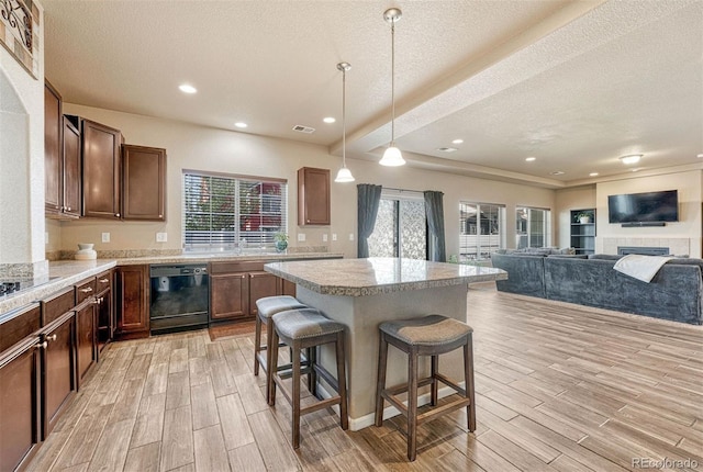 7963 Bonfire Trl, Fountain, CO 80817 - kitchen featuring dishwasher, light wood-style flooring, a textured ceiling, a kitchen island, and light countertops