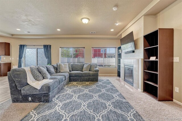 7963 Bonfire Trl, Fountain, CO 80817 - living room with a textured ceiling, carpet floors, healthy amount of natural light, a tiled fireplace, and baseboards