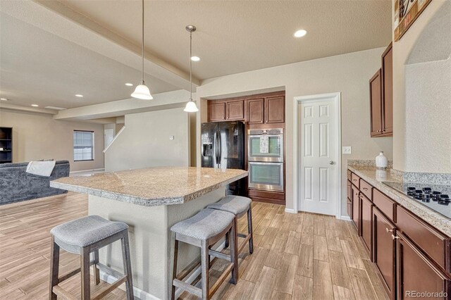 7963 Bonfire Trl, Fountain, CO 80817 - kitchen with a breakfast bar, light wood-style floors, black appliances, light countertops, and a center island