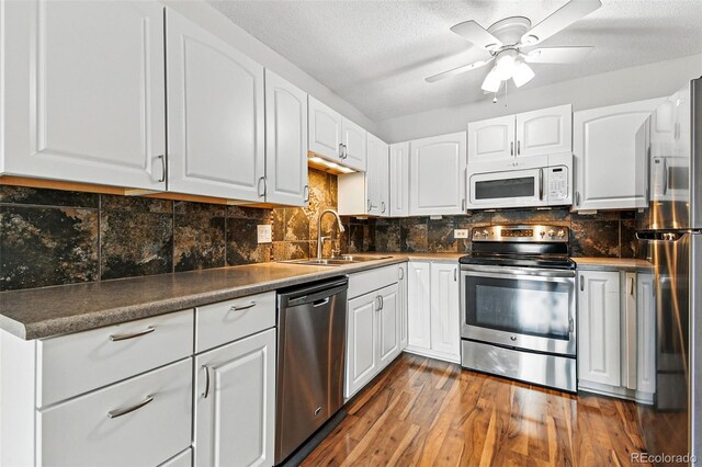 kitchen featuring a sink, appliances with stainless steel finishes, dark wood finished floors, white cabinets, and ceiling fan