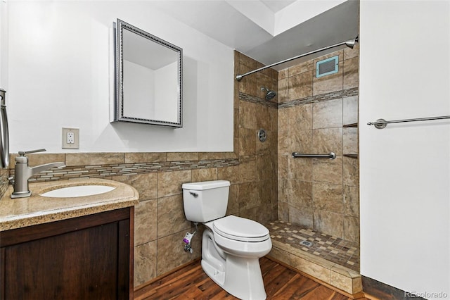 full bathroom with a tile shower, toilet, vanity, and visible vents