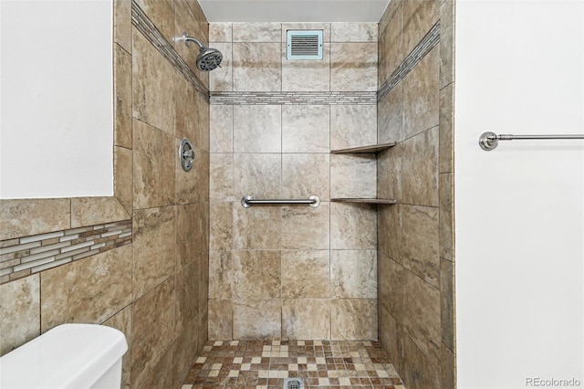 bathroom featuring a tile shower, visible vents, and toilet