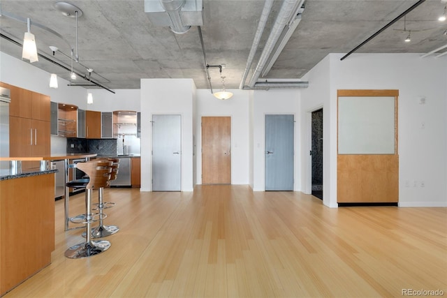 kitchen featuring light wood finished floors, tasteful backsplash, dishwasher, modern cabinets, and glass insert cabinets