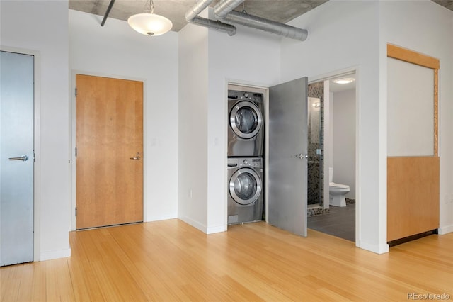 washroom with laundry area, stacked washer / dryer, and wood finished floors