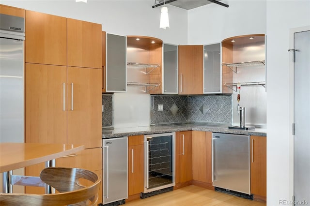 kitchen featuring wine cooler, fridge, tasteful backsplash, stainless steel built in refrigerator, and dark stone countertops