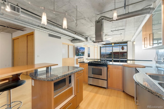 kitchen with light wood-type flooring, visible vents, island range hood, and stainless steel appliances