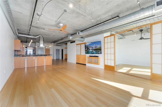 unfurnished living room featuring light wood-type flooring and ceiling fan