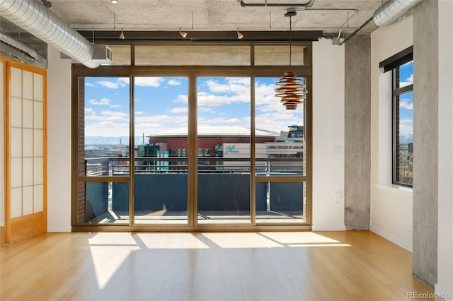 empty room with a wall of windows and wood finished floors